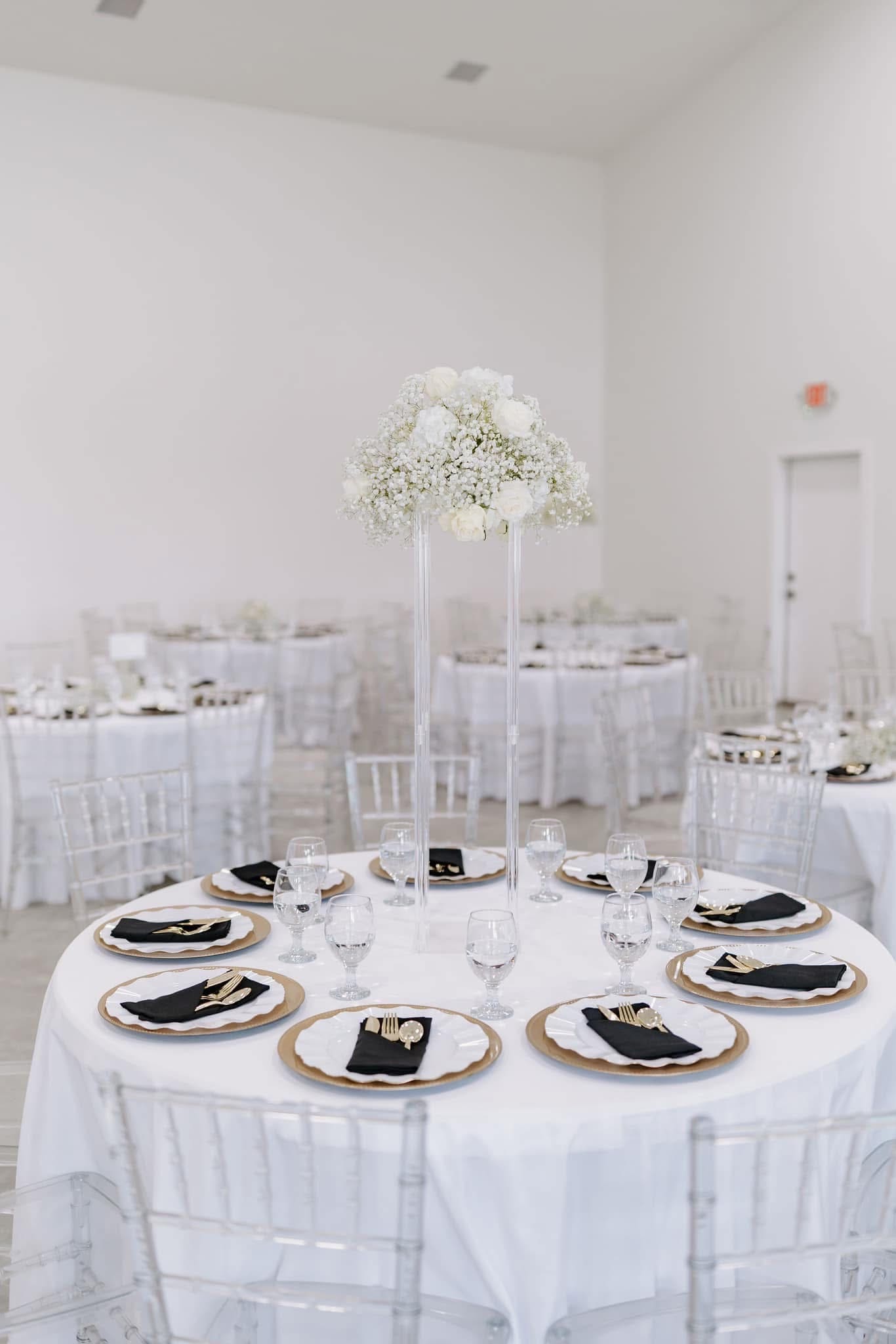 white and gold wedding reception tablescape with tall floral centerpiece